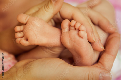 Baby feet in Mother's hands, focus on toes of left foot