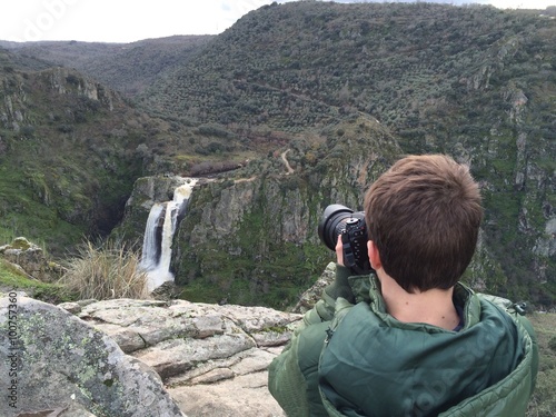 joven fotografiando una cascada con mucho caudal por las intensas lluvias