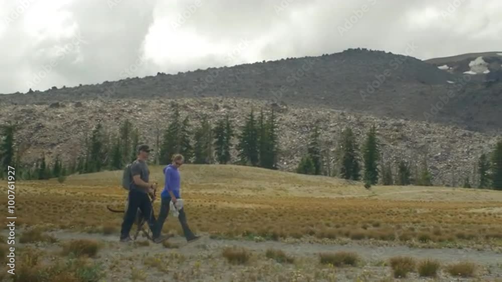 Two hikers walk together with their dog Two hikers walk together with their dog