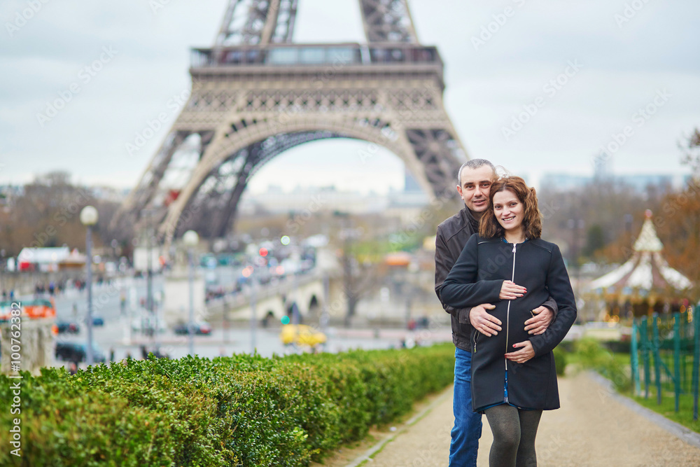 Fotografie Expecting couple together near the Eiffel tower