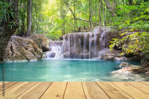 Waterfall  green forest in Erawan National Park in Thailand montage with wooden floor. Landscape with water flow  tree  river  stream and rock at outdoor. Beautiful scenery of nature for vacation.