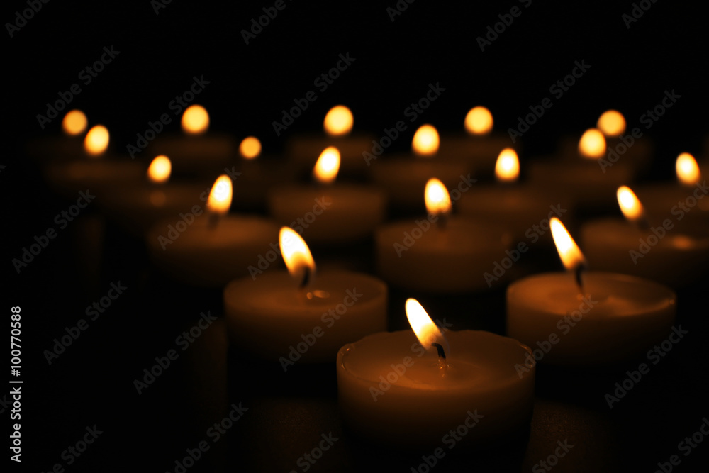 Alight candles in a row on black background