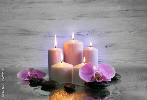 Spa composition with candles  pebbles and flowers on grey  background