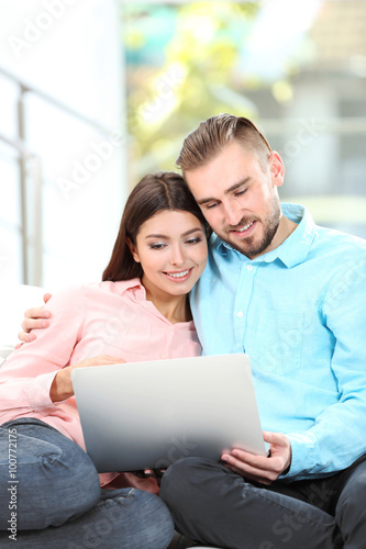 Happy couple sitting on sofa and working on a laptop