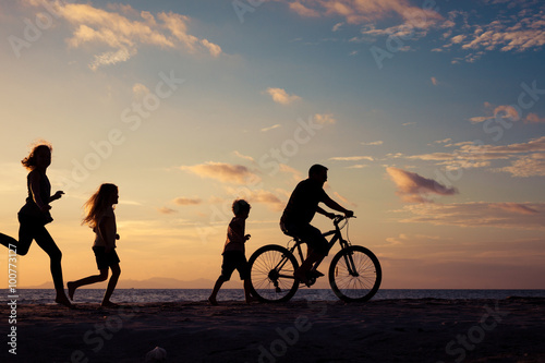 Father and children playing on the beach at the sunset time.