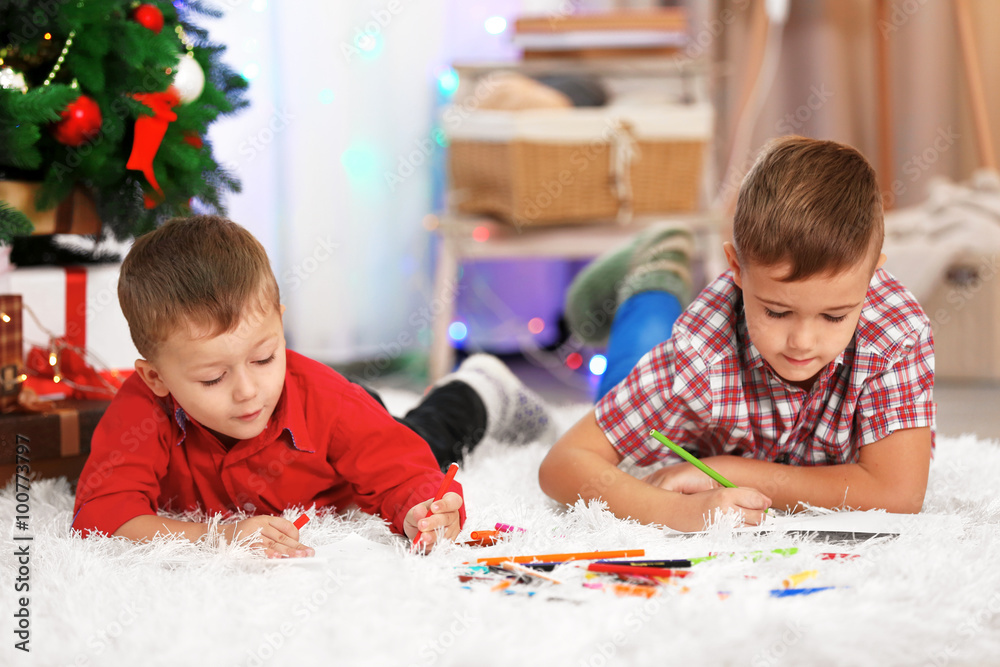 Fototapeta premium Two cute small brothers drawing on Christmas tree background