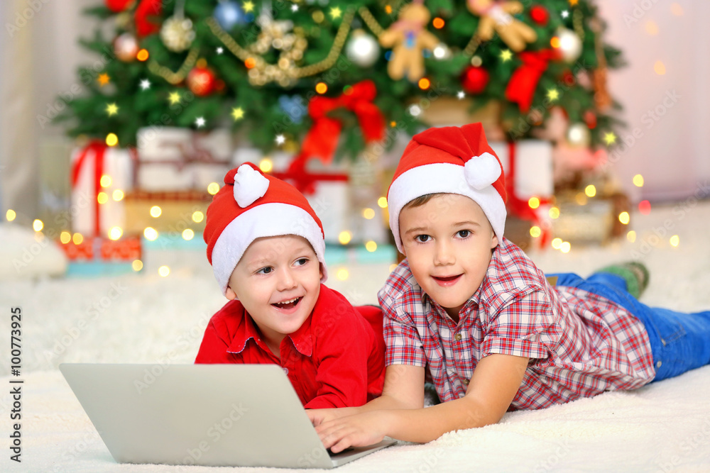 Two cute small brothers using laptop on Christmas decoration background Two cute small brothers using laptop on Christmas decoration background