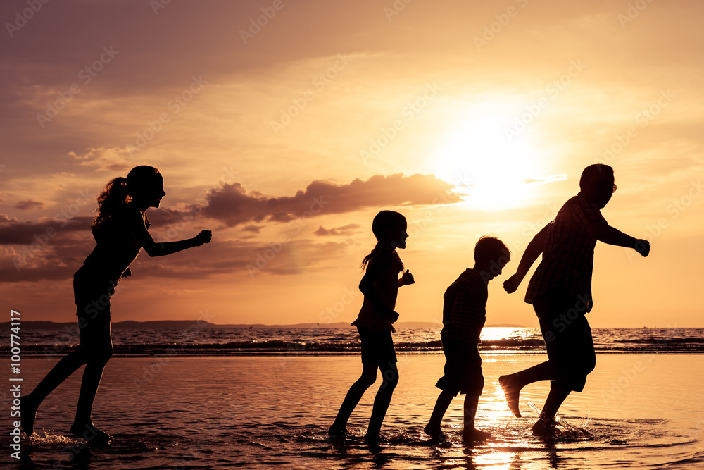 Father and children playing on the beach at the sunset time.