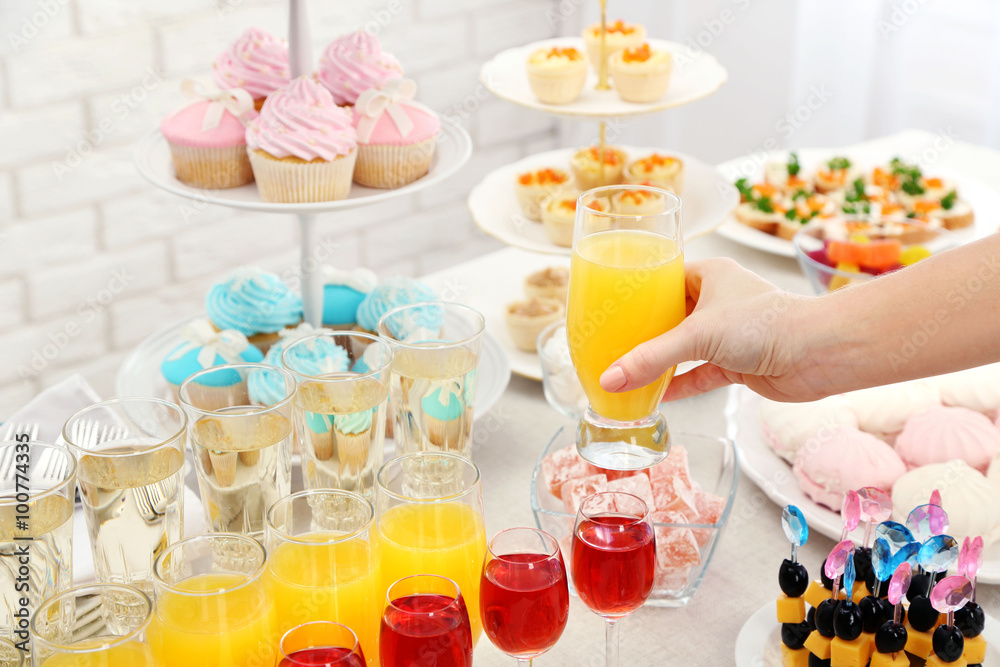 Woman holding glass of juice on buffet background