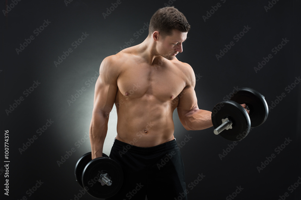 Determined Muscular Man Exercising With Dumbbells