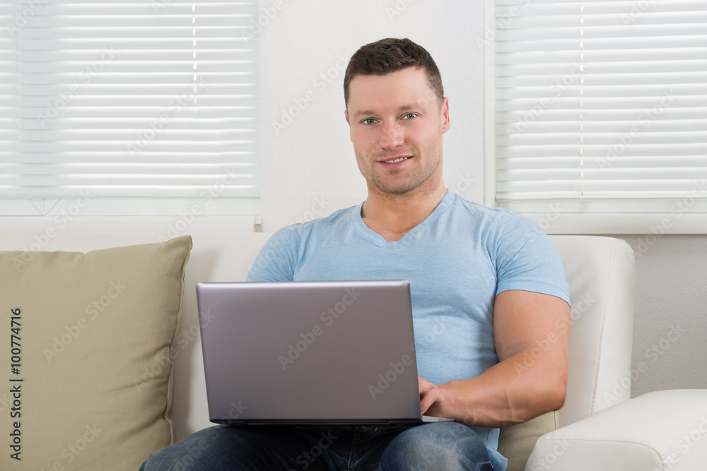 Portrait Of Man Using Laptop On Sofa At Home Portrait Of Man Using Laptop On Sofa At Home