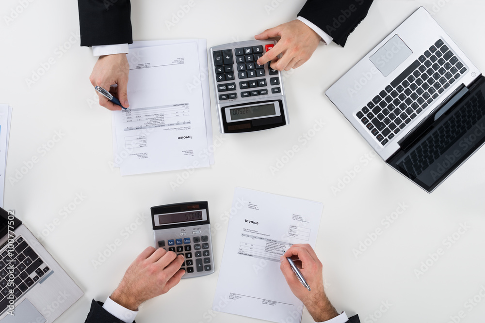 Businessmen Calculating Finance At Desk Businessmen Calculating Finance At Desk
