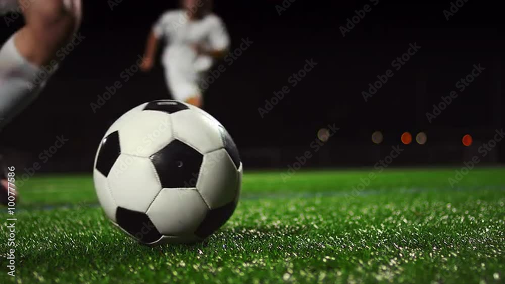 Close up of a soccer ball being kicked in slow motion at night