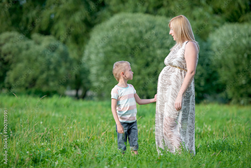 Fototapeta premium Beautiful pregnant woman on a walk with her young son