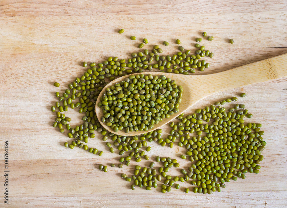 Dry and uncooked mung beans in spoon on wooden background Dry and uncooked mung beans in spoon on wooden background