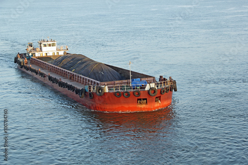 Iron ore mined in hinterland transported to the main harbor in large cargo boat for loading into big ships for exporting in India