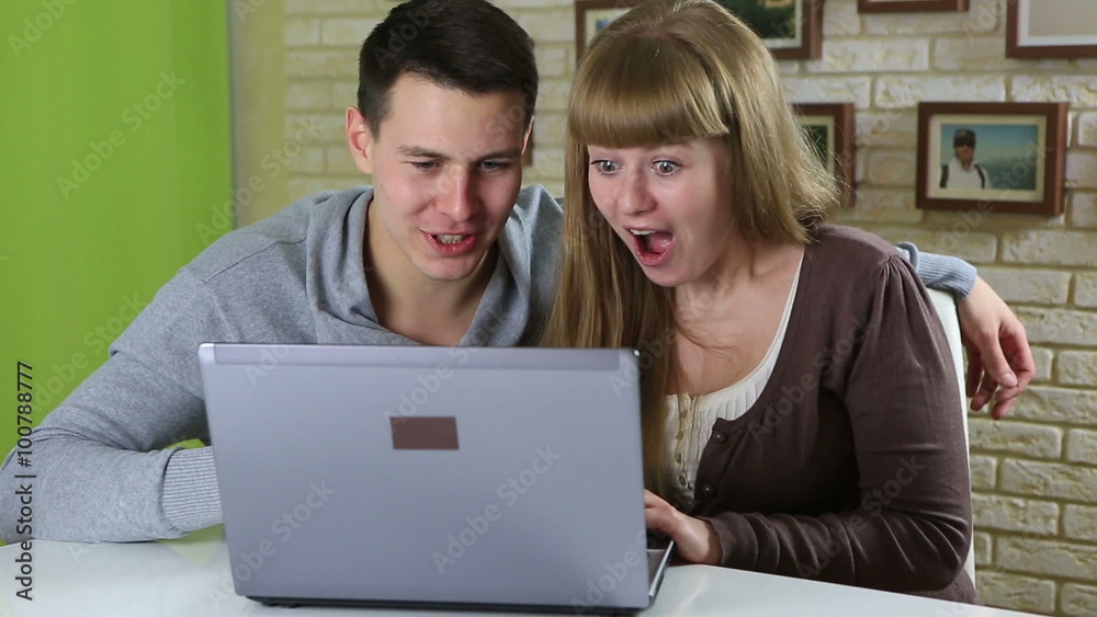 Funny emotional couple to shop online and pay by credit plastic card. Funny emotional couple to shop online and pay by credit plastic card.