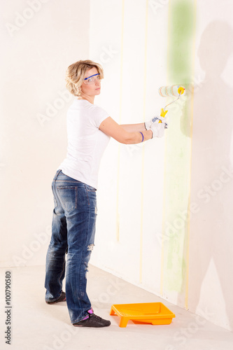 young woman painting wall indoor