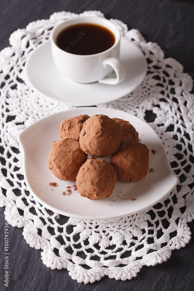 Chocolate truffles on a plate and coffee on the table. vertical
Chocolate truffles on a plate and coffee on the table. vertical