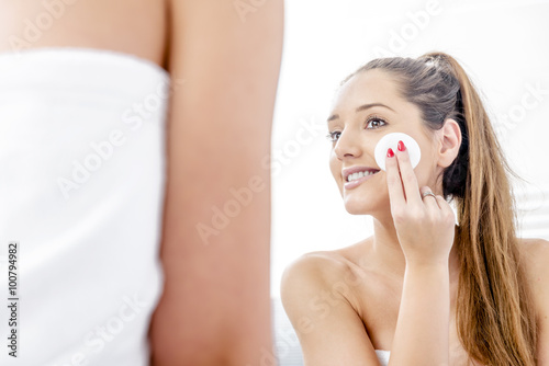 Pretty woman cleaning her face in the bathroom.
