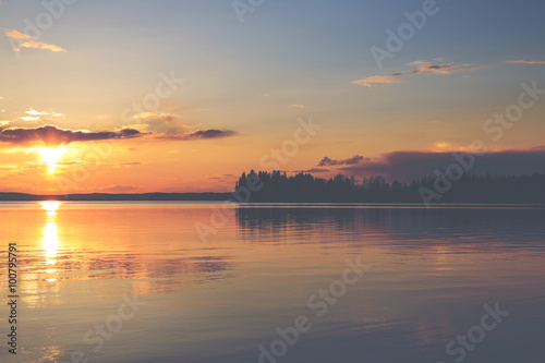 A magnificent sunset by the lake in Finland. Image has a vintage effect applied. © Jne Valokuvaus