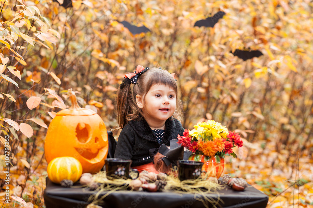 Little girl in the autumn forest of beautifully decorated table for halloween Little girl in the autumn forest of beautifully decorated table for halloween