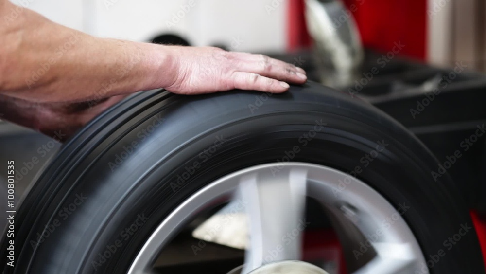 Auto mechanic rolling tire on balancing machine Auto mechanic rolling tire on balancing machine