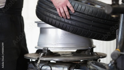 car mechanic takes of the tire from alloy wheel