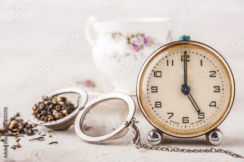 Vintage alarm clock with tea strainer on the white table