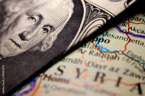 A dollar bill (figuring George Washington) on top of a map of Syria photo