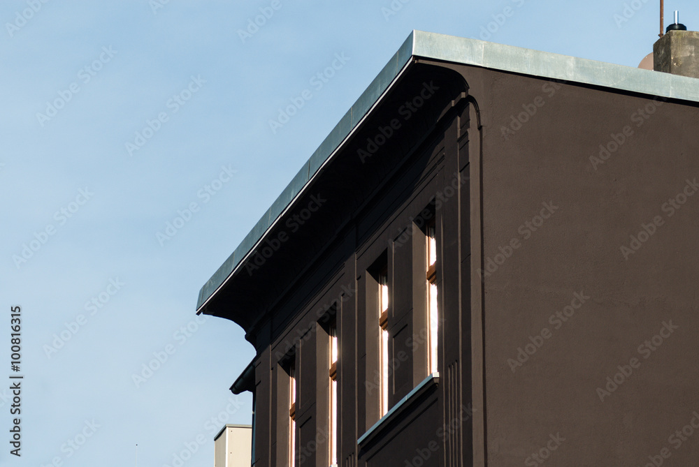 Privatgebäude im Sonnenschein, blauer Himmel, Fensterfront, dunkle Fassade.