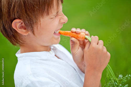 kid eating a carrot on the grass 