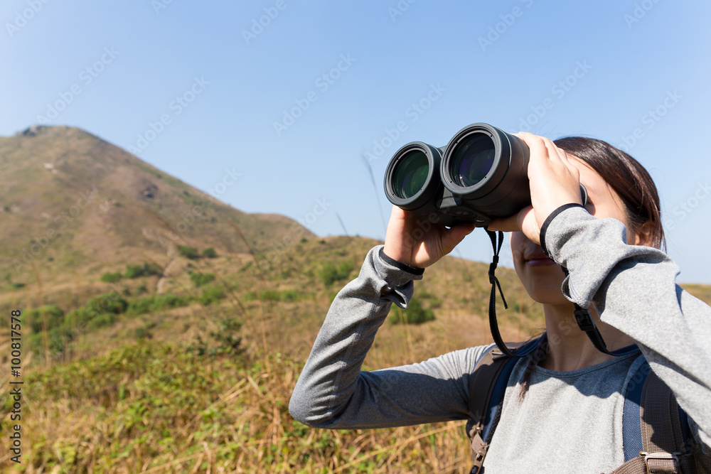 Woman looking though binocular when going hiking