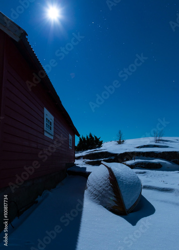 old boat covered in snow lightened by a fullmoon  photo