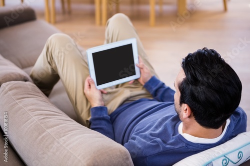 Man using tablet lying on the couch