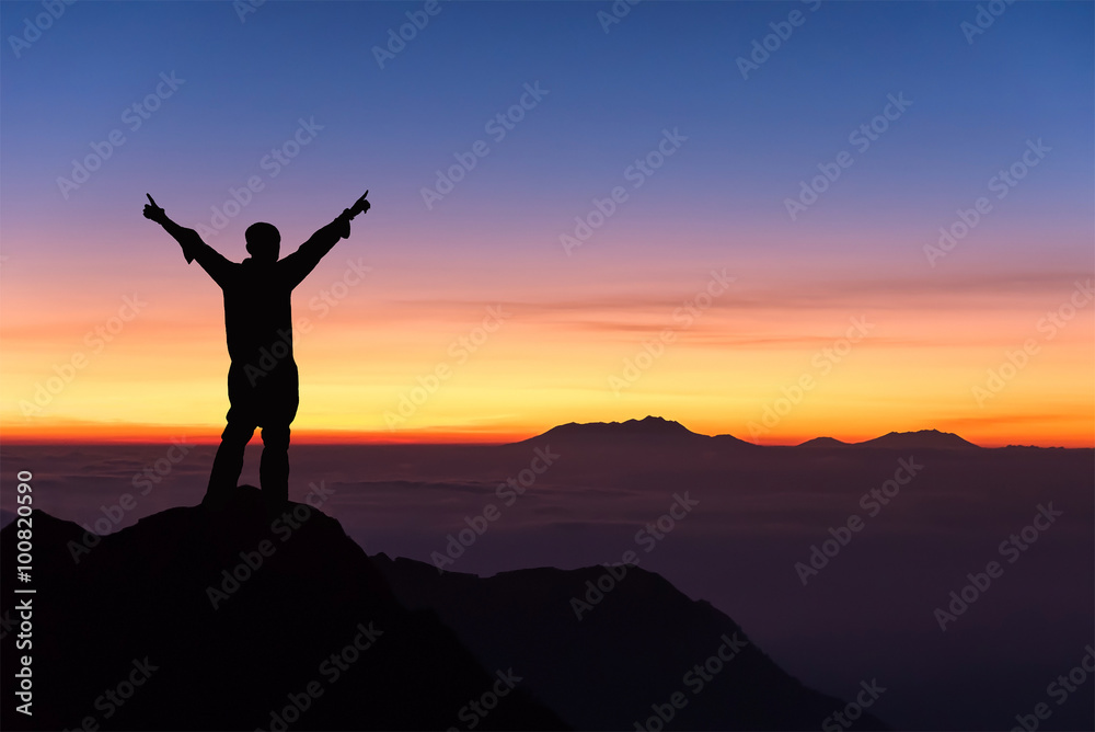 silhouette of man standing and spread hand on the top of mountai