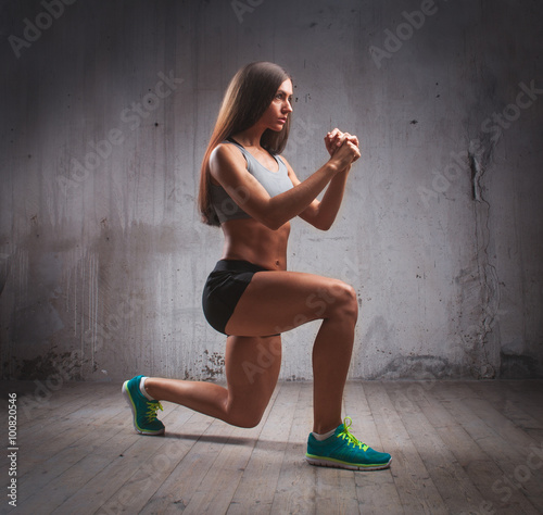 Young fit muscular woman doing lunge in brutal interior photo