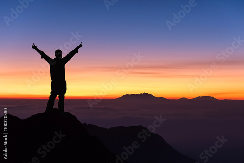 silhouette of man standing and spread hand on the top of mountai © chanwitohm