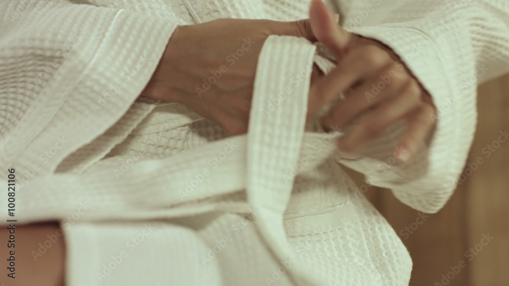 Girl in sauna tying belt on the robe