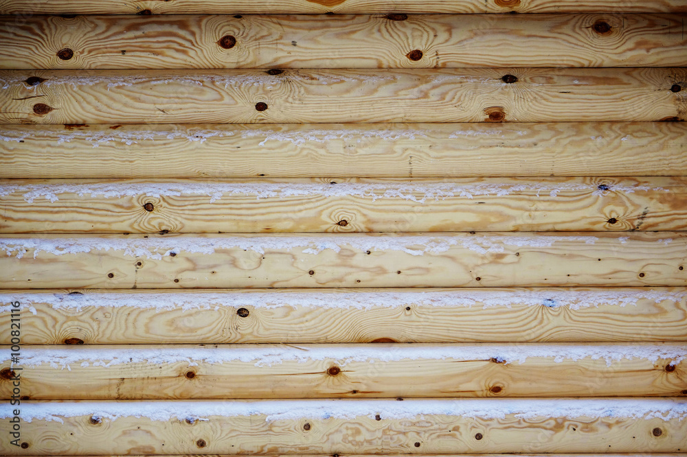 Natural background of the wooden wall of the new logs. Light shade. Logs snowing. Natural background of the wooden wall of the new logs. Light shade. Logs snowing.