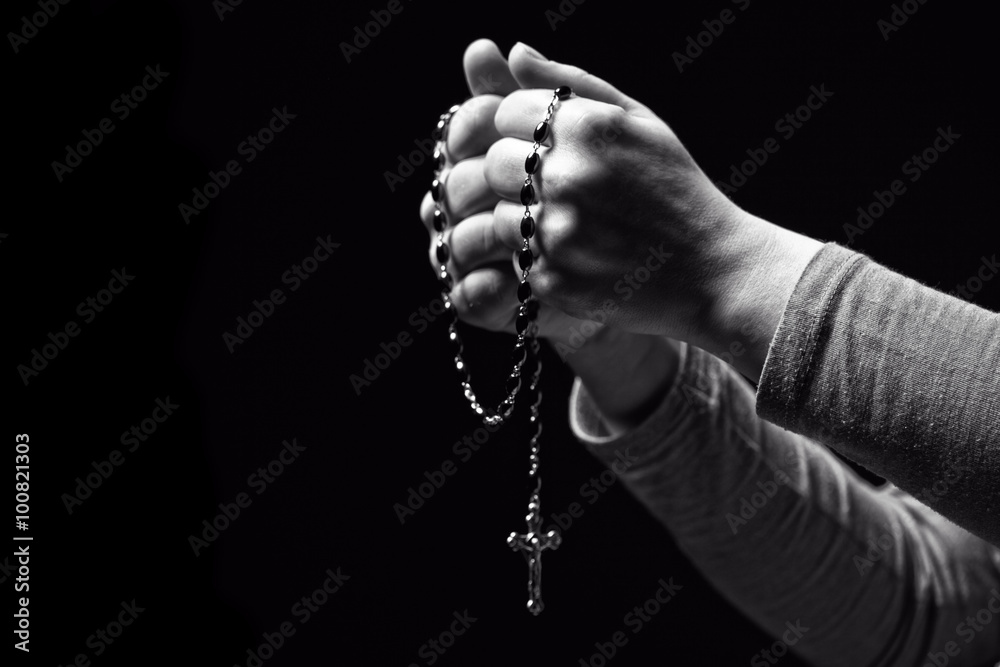 Obraz premium christian rosary in hands. black background. faith, religion, belief