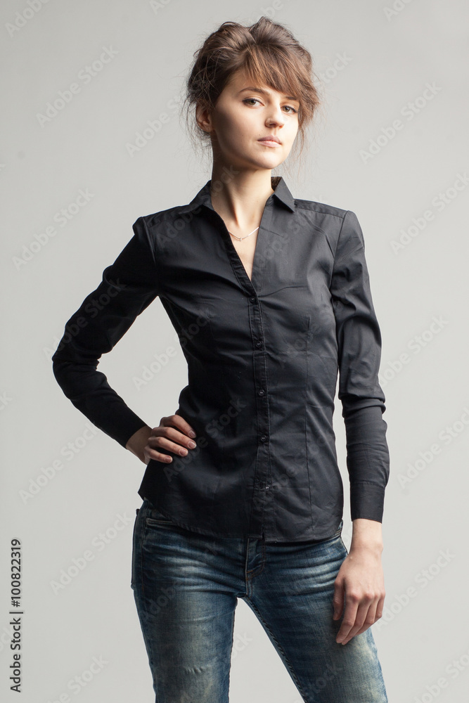 Young beautiful caucasian woman in black shirt and jeans on gray background Young beautiful caucasian woman in black shirt and jeans on gray background