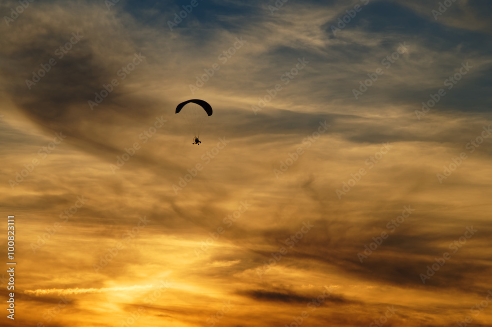 Paragliding high in the clouds at sunset. Silhouettes against a background cloudy sky in the colors of the sunset. Paragliding high in the clouds at sunset. Silhouettes against a background cloudy sky in the colors of the sunset.