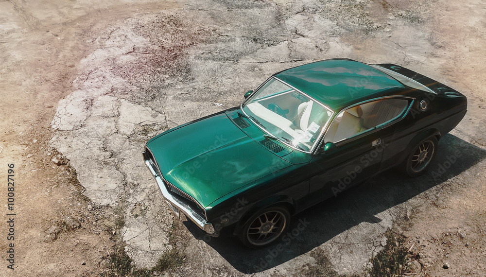 Green muscle retro car on the sand road