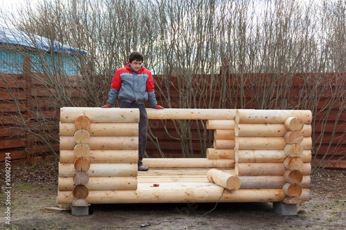 man builds structure made of logs