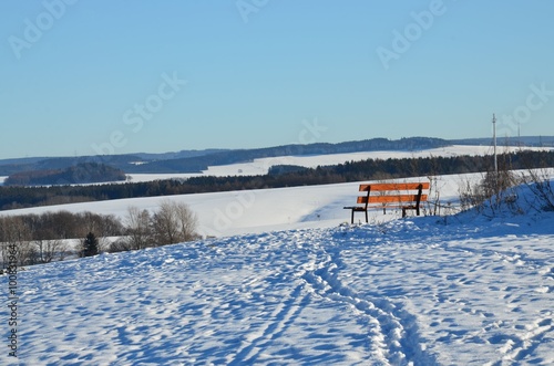 Holzbank in winterlicher Hügellandschaft