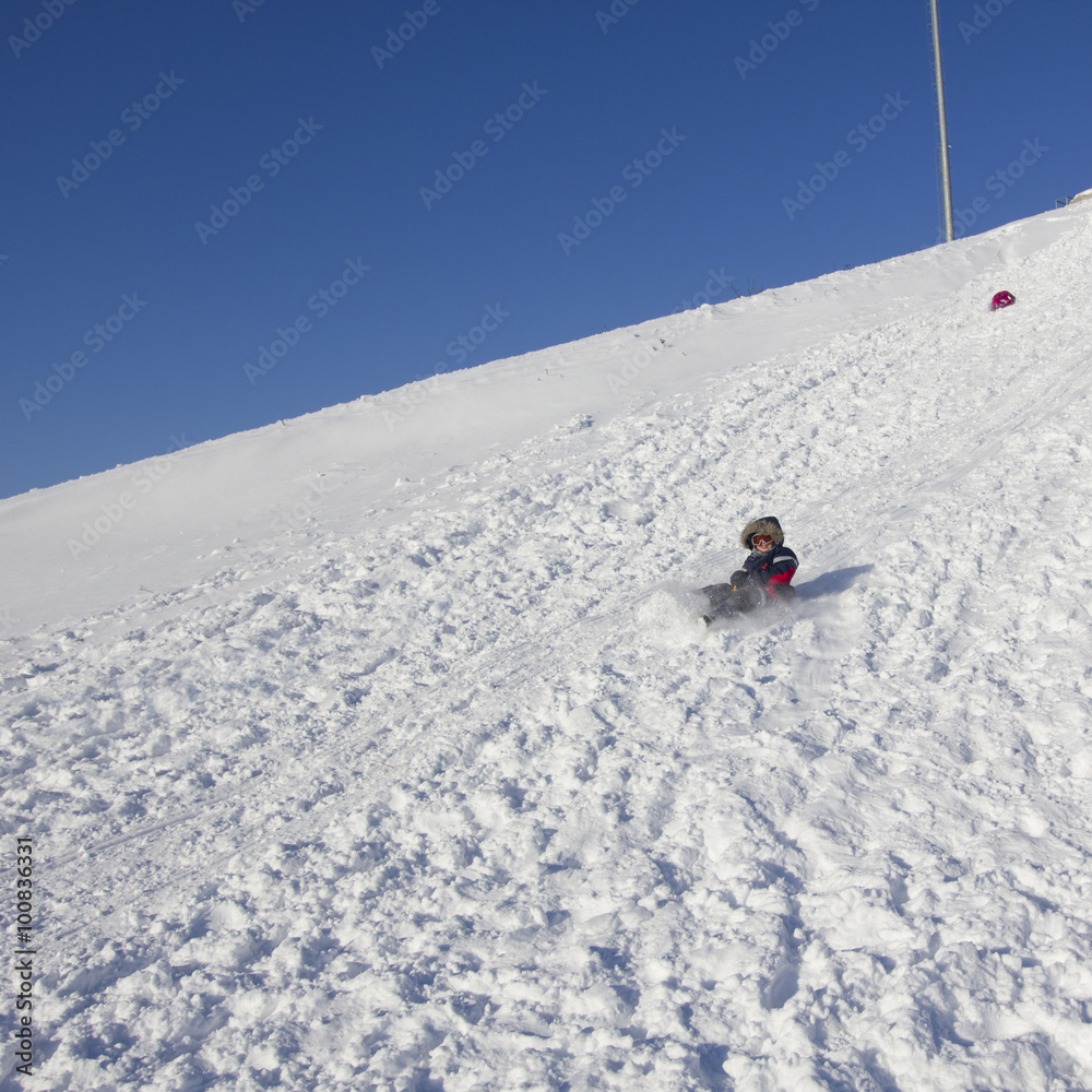 child sledding on a huge winter slope