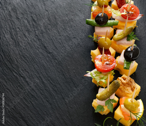 Delicious appetizers with cheese and mix ingredients. Various cheese skewers  on a black background