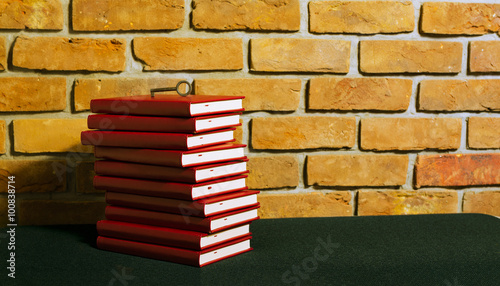 Stos czerwonych książek i klucz na tle ściany z cegły.
