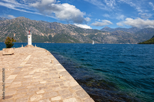 Stone wharf with a beacon against the sea and mountains, Bay of Kotor, Montenegro.